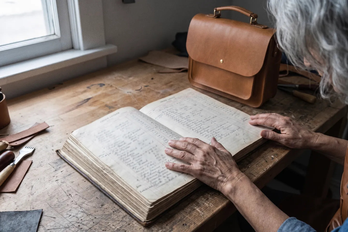 Rose&rsquo;s open order book on the bench, her palm across the page, a finished bag beside it.
